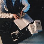 person counting money with smartphones in front on desk 3